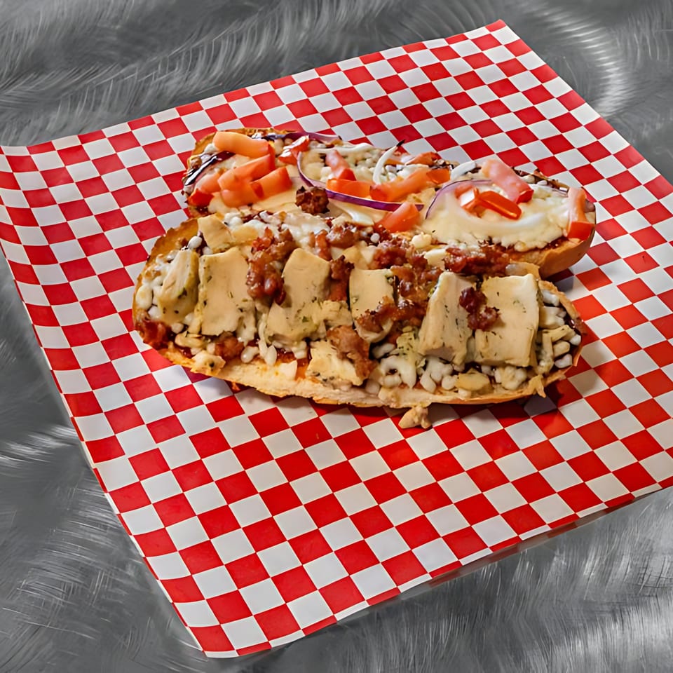 Two loaded pizza bread appetizers with various toppings on red and white checkered paper.